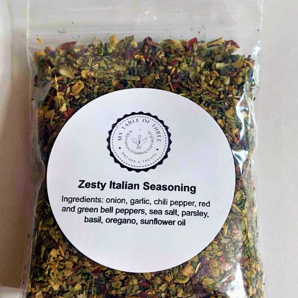 A clear little bag filled with seasoning with a round title label on the front. 